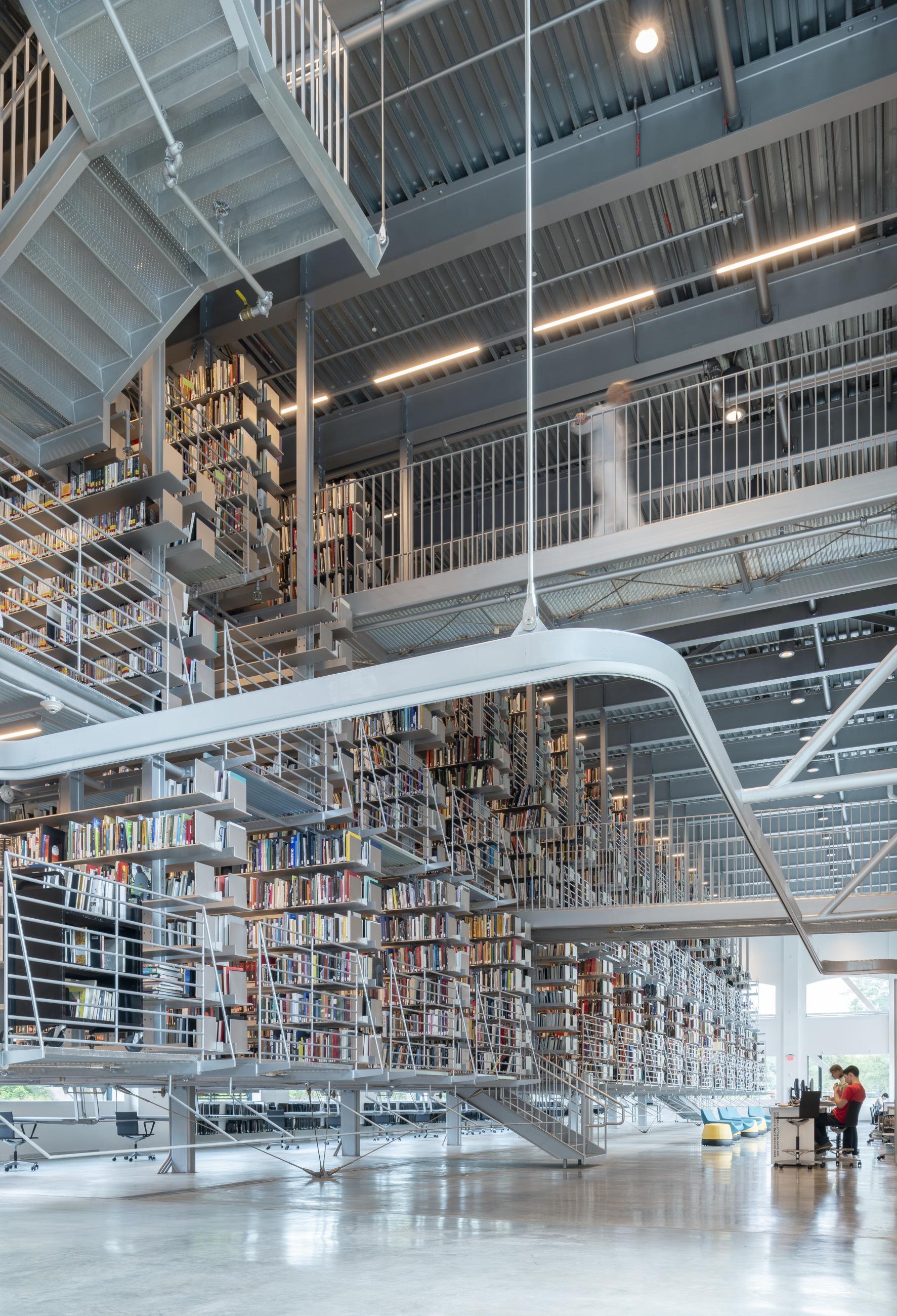 Suspended steel shelving and grating walkways form a floating library stack at Cornell's Mui Ho Fine Arts Library